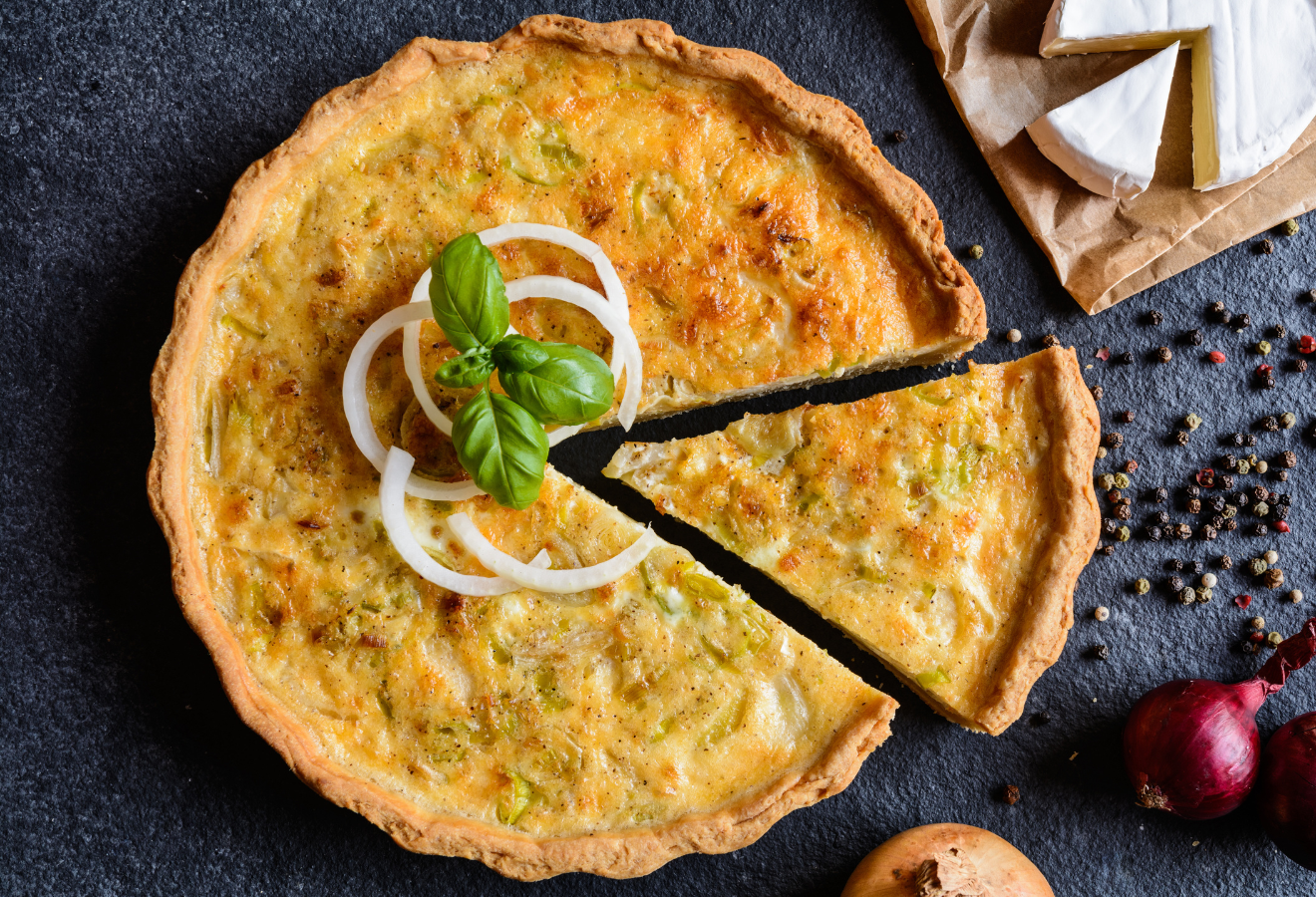 Exotische Zwiebelquiche mit Zwiebelringen und Basilikum garniert