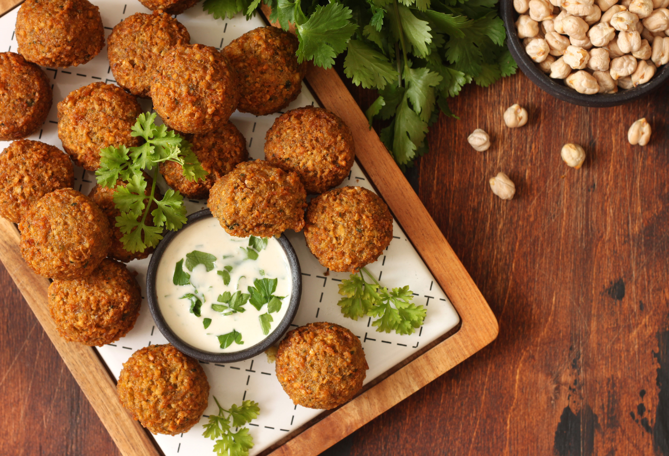 Curry-Falafeln auf einem Brett mit einem Schälchen Soße